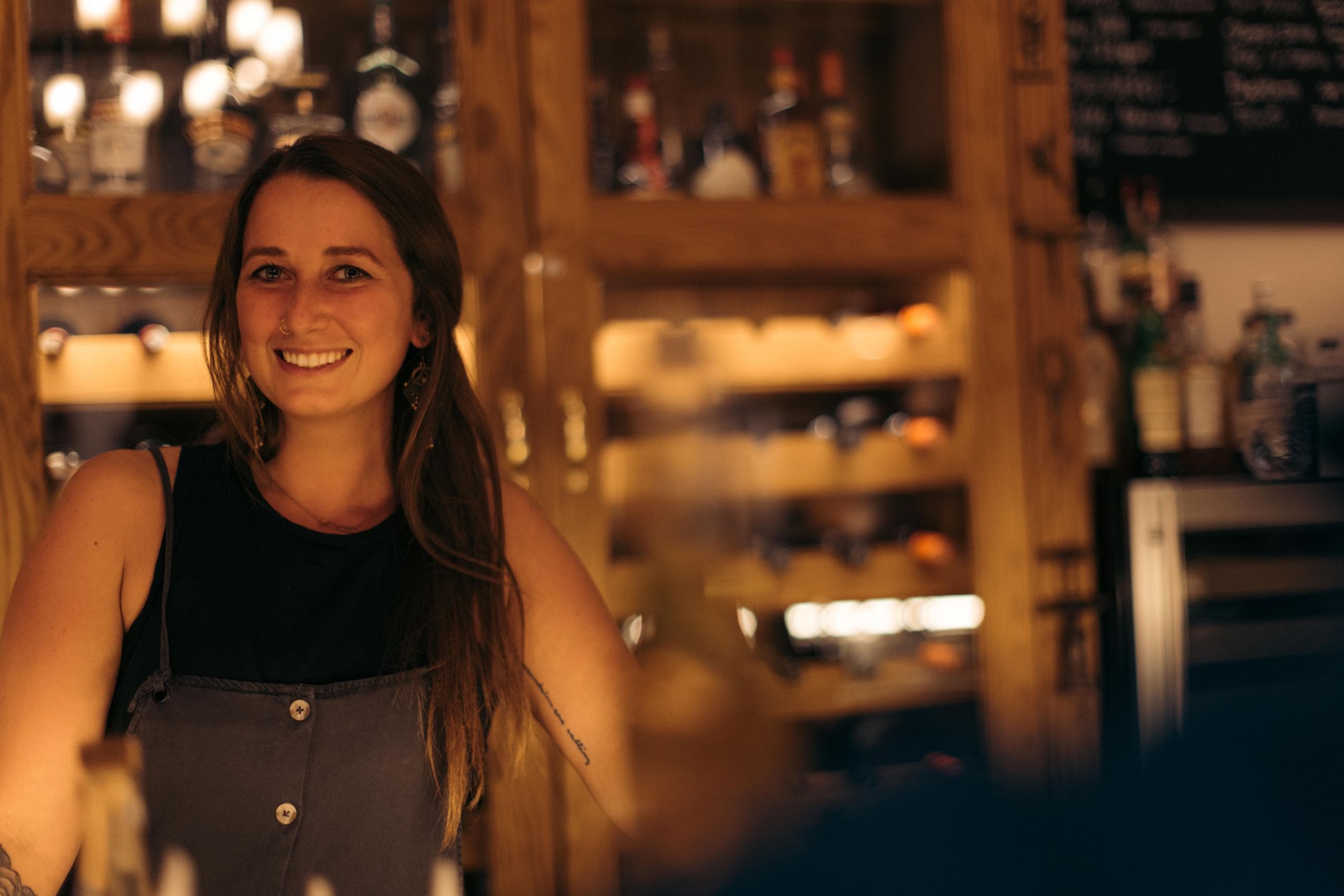 A woman standing behind the bar smiling
