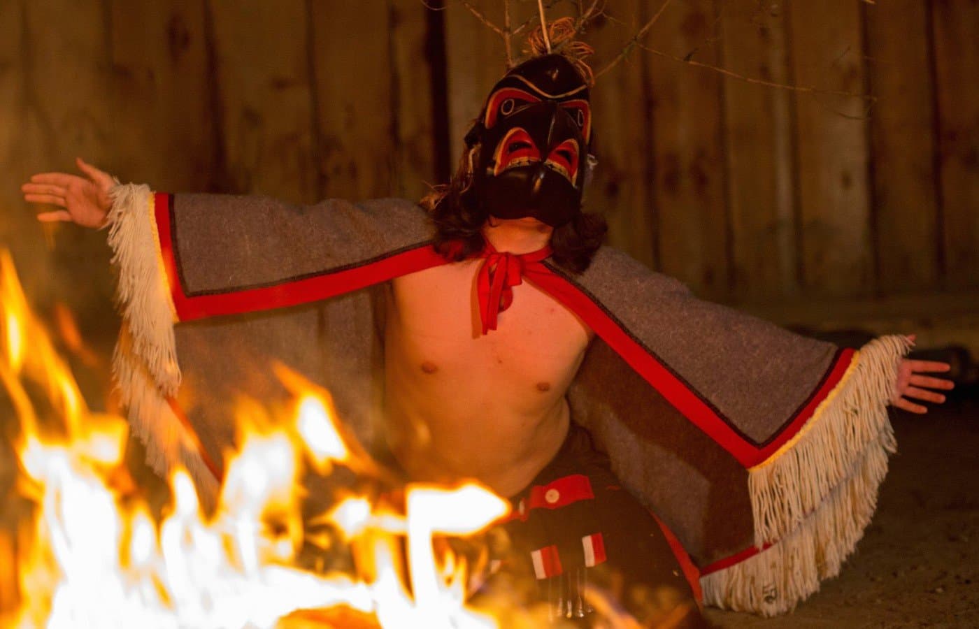 A person in costume dancing by a fire