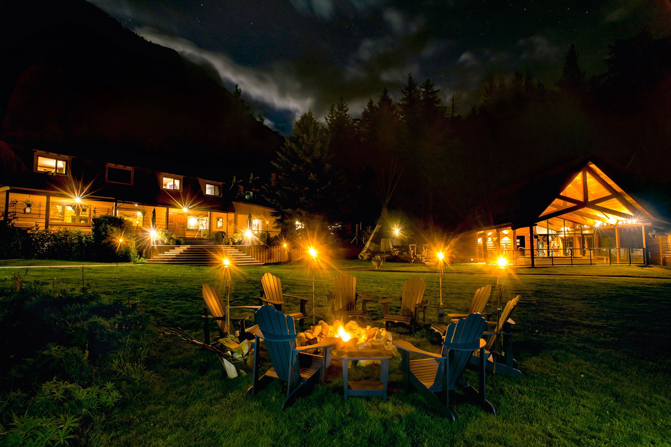 A fire pit with chairs around it at night
